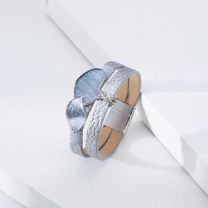 Close-up of leather multilayer bracelet with metal leaves and sparkling X-shaped crystal charm