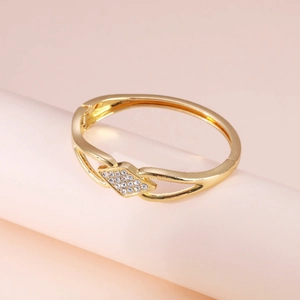 Close-up of gold geometric bangle featuring a diamond-shaped sparkling rhinestone inlay