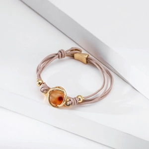 Pulsera multicapa de cuero rosa con gema roja engastada en oro sobre soportes blancos