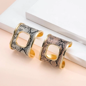 Bracciali rigidi larghi con stampa serpente e ritaglio quadrato su piedistallo elegante