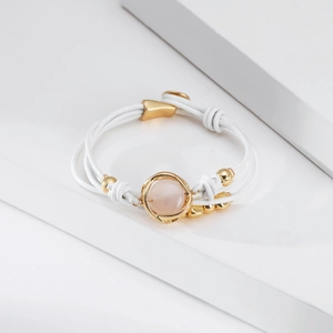 Detalle de pulsera multicapa de cuero blanco con piedra rosa y cuentas doradas