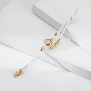 Detalle de pulsera trenzada blanca de varias capas con cuentas rosas y toques dorados