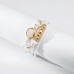 Detalle de pulsera envolvente de cuero blanco con cuentas doradas y colgante rosa