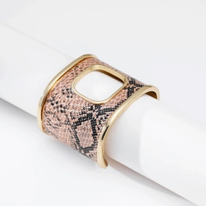 Dettaglio della pelle di serpente rosa su bracciale rigido dorato largo con taglio quadrato