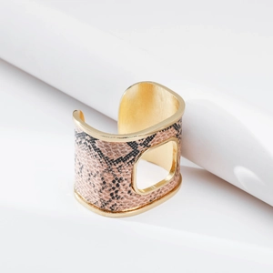 Dettaglio del bracciale rigido dorato con trama a serpente marrone e design con intaglio