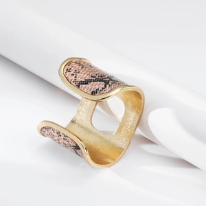 Dettaglio del bracciale rigido dorato con inserto in pelle di serpente rosa e finitura interna