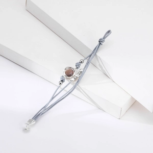 Detalle de una pulsera multicapa de cuero gris con piedra marrón y cuentas de metal plateado