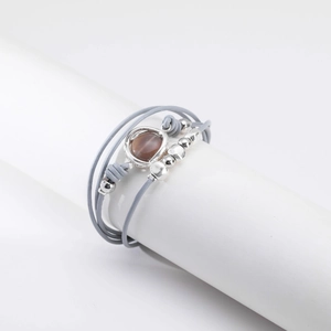 Detalle de pulsera multicapa gris con cuentas plateadas y piedra preciosa marrón