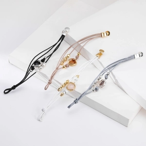 Detalle de pulseras de cuerda multicapa con colgantes de gemas y cuentas metálicas
