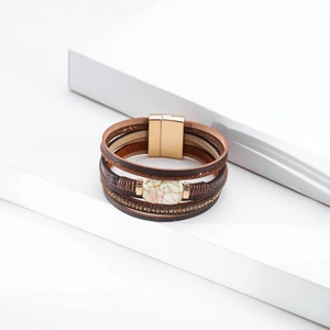 Detail of bohemian multilayer leather bracelet with pearl plate and magnetic gold clasp