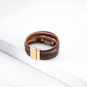 Detail of multi-layer leather bracelet with gold magnetic clasp and faux pearl accents