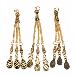Close-up of three vintage gold alloy tassels with leaf and pineapple pendant details