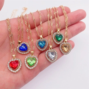 Gros plan de colliers avec pendentifs cœur en acrylique coloré et chaînes dorées