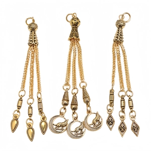 Detailed view of three gold alloy tassels with moon wolf and geometric pendants for prayer beads