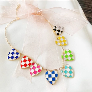 Detailed view of golden necklace with colorful checkered enamel heart pendants
