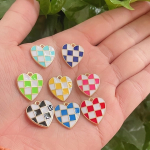 Detail of colorful checkerboard heart pendants in palm to show DIY jewelry size