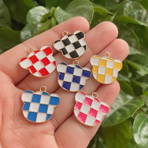 Close-up of colorful checkered oil-drop bear pendants held in hand for DIY jewelry making
