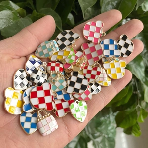 Macro shot of colorful checkerboard enamel heart and handbag charms on a green leaf