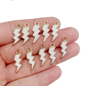 White lightning bolt pendants on hand showing size for DIY jewelry making crafts