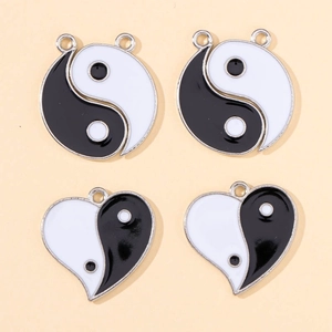 Detailed view of four black and white Yin Yang heart and round alloy charms for DIY jewelry