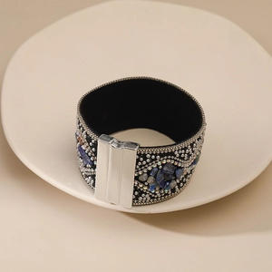 Detalle de brazalete ancho bohemio con piedras azul oscuro y cierre magnético metálico