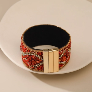 Primer plano del brazalete bohemio con piedras rojas y cierre magnético en color oro