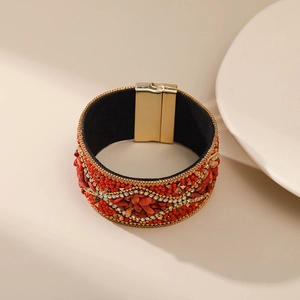 Detalle de brazalete bohemio con cuentas rojas y cierre magnético dorado elegante