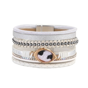Detail van meerlaagse leren armband met strasbanden en bedeltje met koeienprint