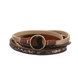 Dettaglio di bracciale boho multistrato con pelle maculata e ciondoli in metallo