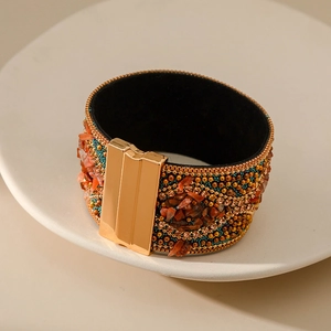 Detalle de pulsera bohemia magnética con piedras naranjas y cuentas doradas en bandeja cerámica
