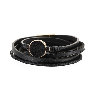 Dettaglio di un bracciale in pelle multistrato con anello d'oro e inserto in ecopelliccia