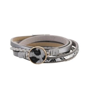 Dettaglio del bracciale a più strati con ciondolo maculato e cinturini in pelle grigia