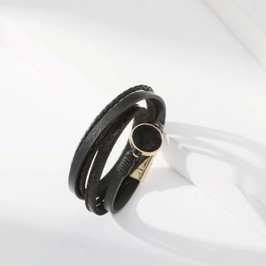 Dettaglio del bracciale in pelle nera multistrato con chiusura magnetica dorata e cerchio