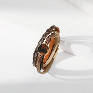 Dettaglio macro del bracciale multistrato in pelle leopardata con ciondolo tondo