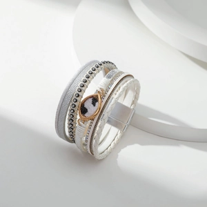 Detail van een meerlaagse leren armband met kristallen en een oogvormige hanger