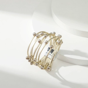 Detail van een gelaagde gouden metalen armband met kleine kralen en zilveren sluiting