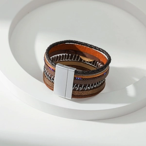 Detail van meerlagige lederen armband met zilveren magneetsluiting en strass-accenten