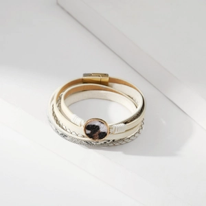 Dettaglio di bracciale a più strati in pelle serpentata e anello in metallo leopardato