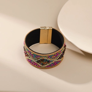 Primer plano detallado de la pulsera bohemia con cuentas, pedrería y hebilla dorada