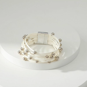 Detail van de meerlaagse witte koordarmband met zilveren kralen en magnetische sluiting