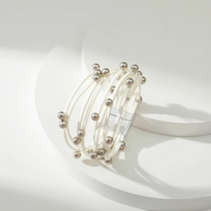 Detailopname van witte meerlaagse leren armband met zilveren kralen op display