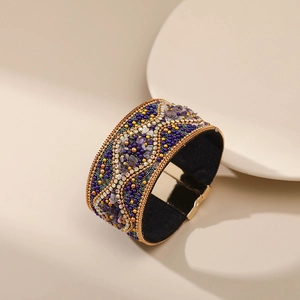 Detalle de brazalete bohemio con cuentas, cristales púrpuras y cierre magnético dorado
