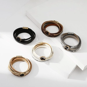 Dettaglio di bracciali multistrato in pelle con ciondoli leopardati e chiusure magnetiche