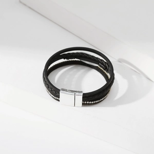 Detail eines mehrlagigen schwarzen Lederarmbands mit Kristallbesatz und Magnetschließe