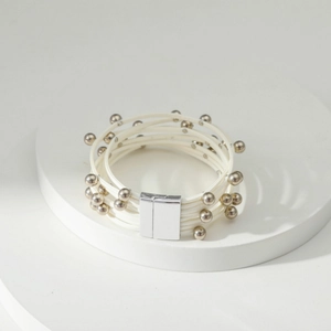 Detailopname van een witte meerlaagse armband met zilveren kralen en magnetische sluiting