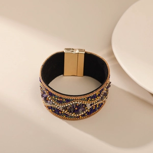 Detalle de pulsera bohemia con cuentas púrpuras y cierre magnético dorado