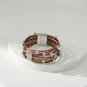 Detail van meerlaagse bruine leren wikkelarmband met zilveren kralen en magneetsluiting