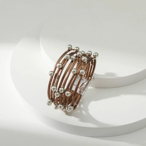 Detail van een meerlaagse bruine leren armband met zilveren kralen en magnetische sluiting