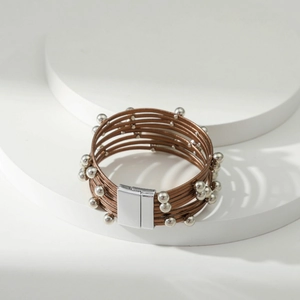 Detail van bohemien meerlaagse bruine leren armband met zilveren kralen en magneetsluiting
