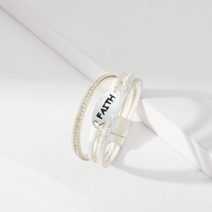 Detail der Faith Metallplatte auf dem weißen mehrlagigen Lederarmband mit Magnetverschluss